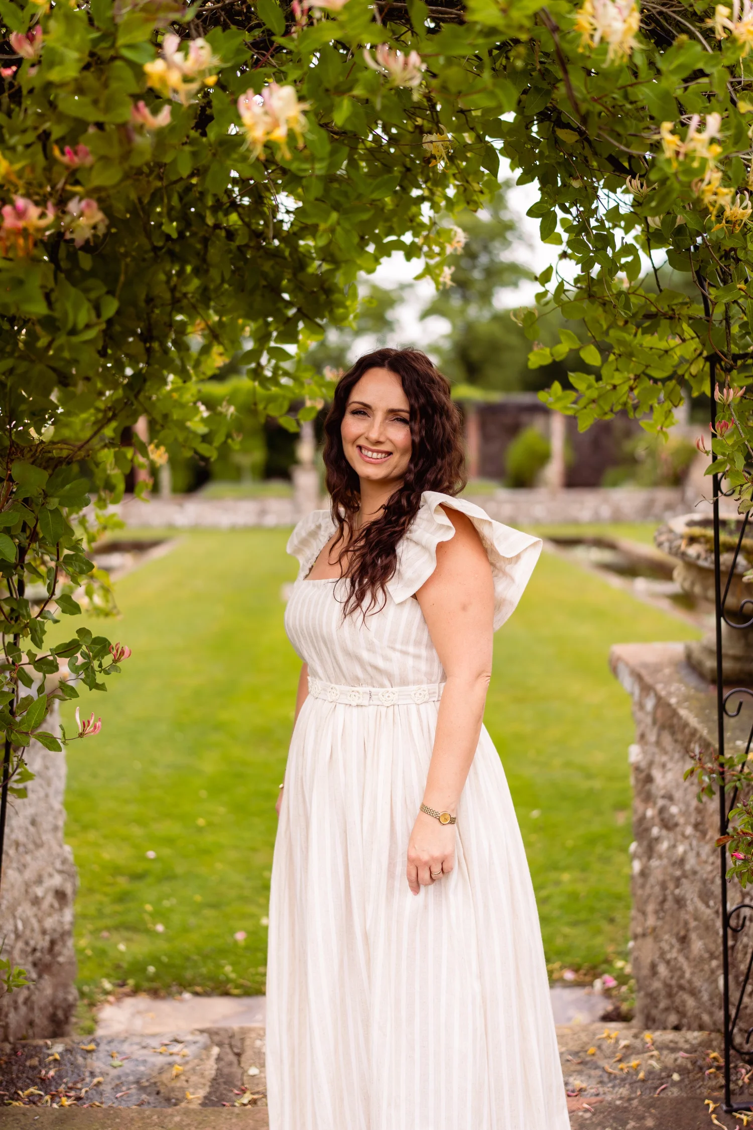 Sally Ashworth in a white dress, standing on a garden lawn