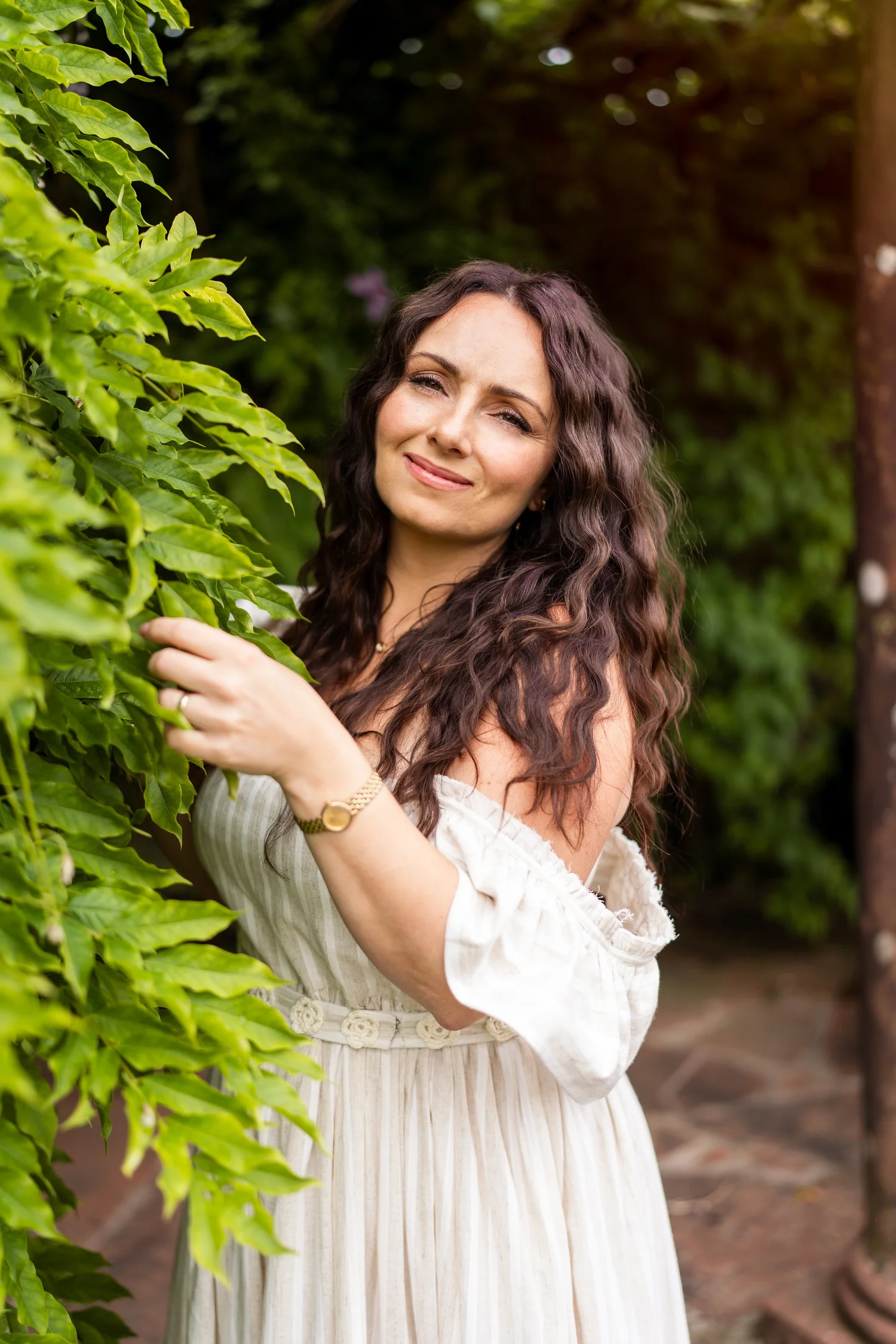 Sally Ashworth smiling among green leaves in a garden