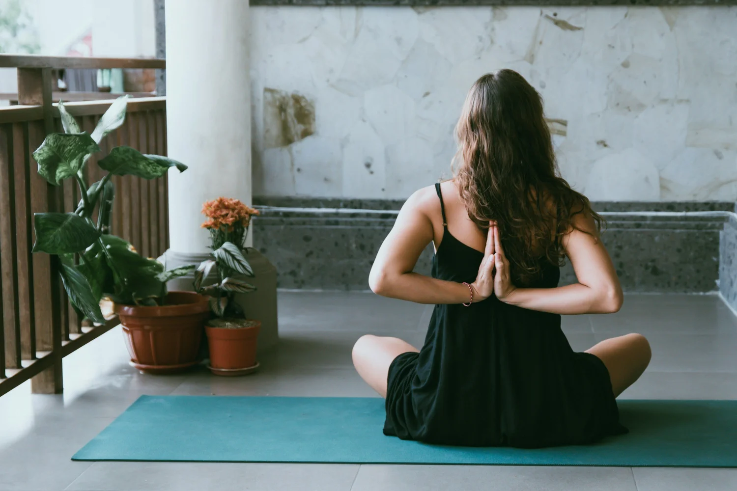 Sally Ashworth seated cross-legged on a mat, hands together, facing the window